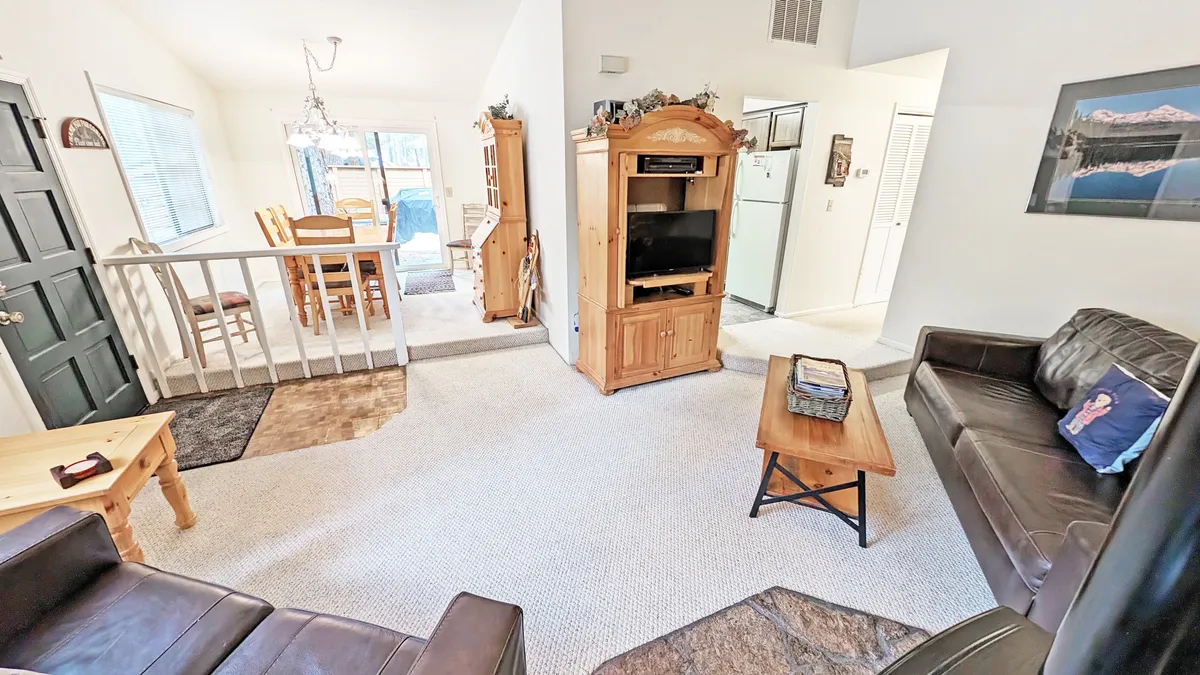 The image showcases a cozy, inviting living area with plush seating, a warm dining table set for family meals, and an entertainment center ready for movie nights. Natural light fills the room, highlighting the open layout ideal for relaxing and spending time together.