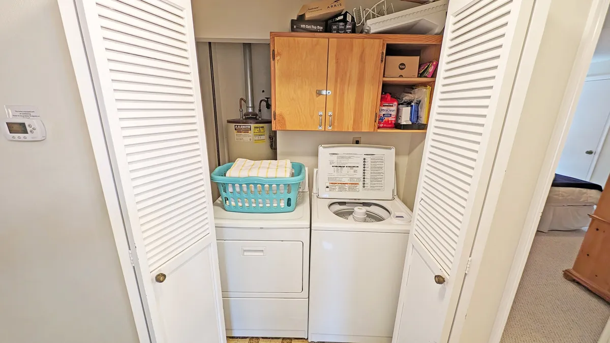 A well-organized laundry room featuring a washer and dryer, a laundry basket, and wooden cabinets for storage. The space is practical and tidy, emphasizing ease of use after a busy day outdoors.